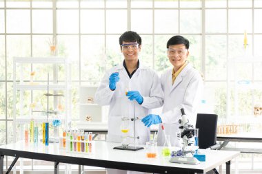 Bilim, Kimya, Teknoloji, Biyoloji ve Laboratuar Konsepti - Asyalı kıdemli ve kıdemsiz bilim adamlarının portresi deney bardağı şişesindeki deneysel sonuçlarından memnun.