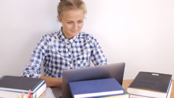 Aantrekkelijk meisje werken achter laptop omgeven door boeken — Stockvideo