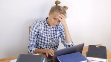 Bir dizüstü bilgisayar çalışan yorgun genç kız