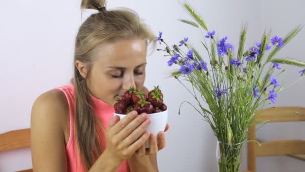 Mujer come una fresa grande y sonríe — Vídeos de Stock