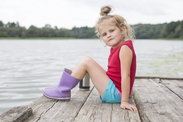 La niña bonita está sentada en el puente. —  Fotos de Stock