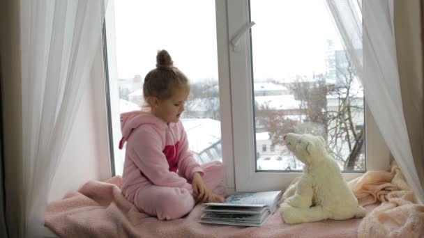 Tjej läser en bok till en leksak Björn — Stockvideo