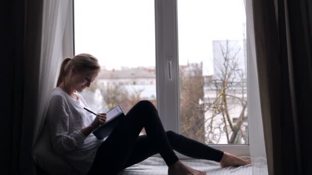 Flickan skriver i sin dagbok och drömmar — Stockvideo