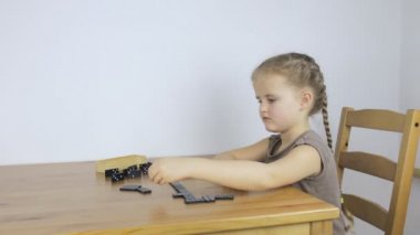 Küçük bir kız yalnız domino oynar