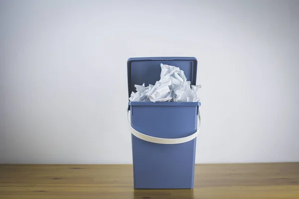 Trash bin with lid completely full of crumpled documents