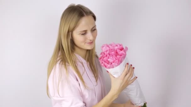 Mujer joven sosteniendo un ramo de tulipanes y sonriendo bonita — Vídeo de stock