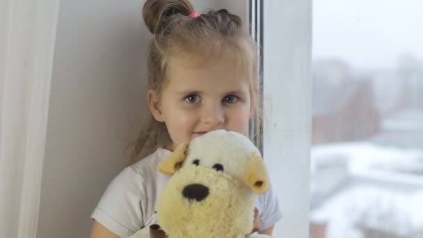 Niña sosteniendo un juguete y mirando a la cámara — Vídeos de Stock