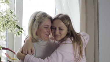 Anne ve kızı gülmek ve ayakta pencere kenarına sarılmak