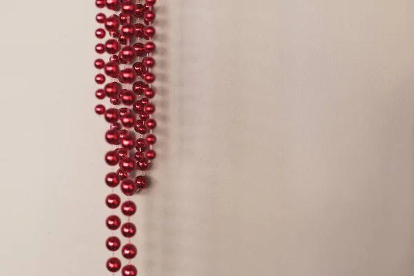 Стіна світло-коричневого кольору, на якому красиво висять червоні намистини — стокове фото