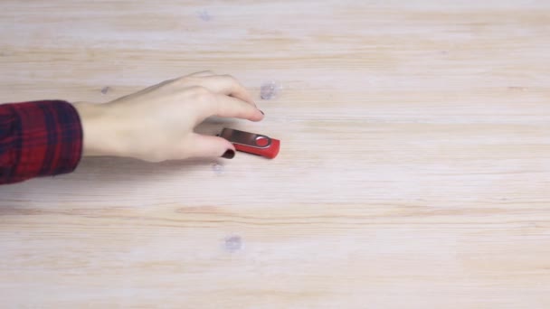 La mano femenina recoge una unidad flash de una mesa de madera — Vídeos de Stock