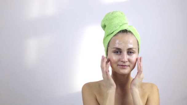 Ung kvinna efter att ta bad att sätta grädde på hennes ansikte — Stockvideo
