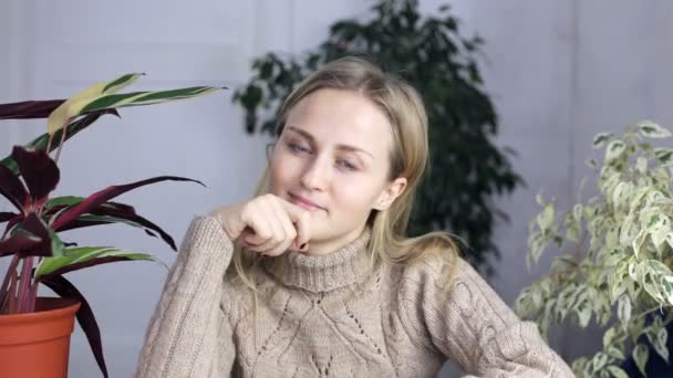 Uma mulher está sentada à mesa e olhando atentamente para a câmera — Vídeo de Stock