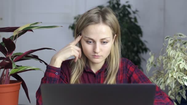 Συλλογισμένος ελκυστικό κορίτσι να κάθεται και να φαίνεται στην οθόνη του φορητού υπολογιστή — Αρχείο Βίντεο