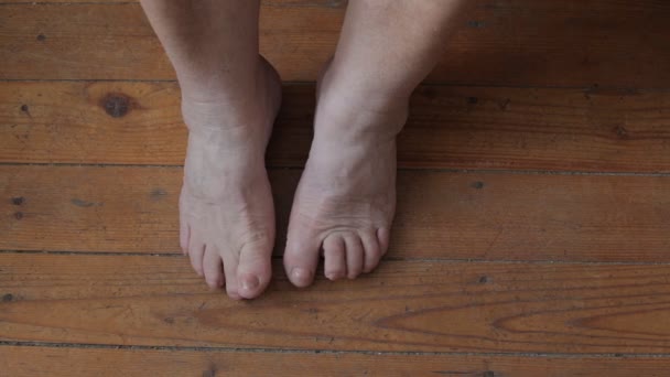 Старые женские ноги стоят на деревянном полу — стоковое видео
