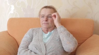 Yaşlı güzel kadın gözlüklerini düzeltiyor