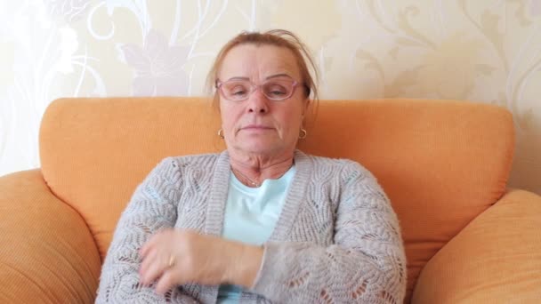 Зрелая женщина в очках задумчиво смотрит в камеру — стоковое видео