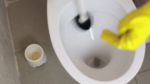 Meisje met rubberen handschoenen reinigt het toilet met een borstel — Stockvideo