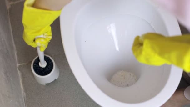 Женщина чистит туалет в резиновых перчатках щеткой — стоковое видео
