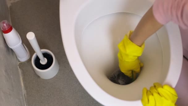 Zenske ruku v žluté rukavice s houbou čištění záchodové mísy
