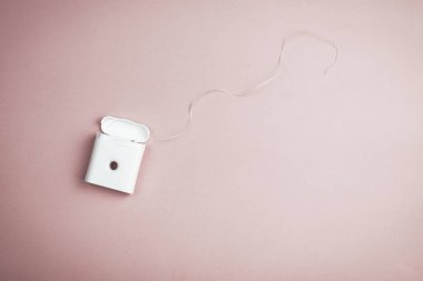 Pembe arka plan üzerinde beyaz plastik bir kapta diş ipi