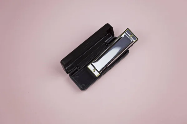 Harmonica in container on a pink background — Stock Photo, Image