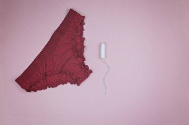 Pembe bir arka plan üzerinde kırmızı kadın külot ve beyaz tampon