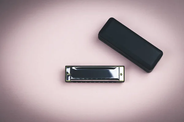 Metal harmonica and a black box on dirty pink background — Stock Photo, Image