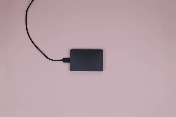 Modern black external hard drive with a black cable for connecting to a computer