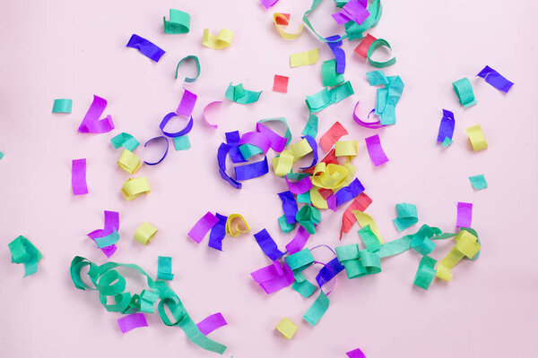 Multicolored paper confetti on a pink background