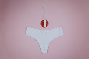 Pembe arka planda tampon olan beyaz külot.