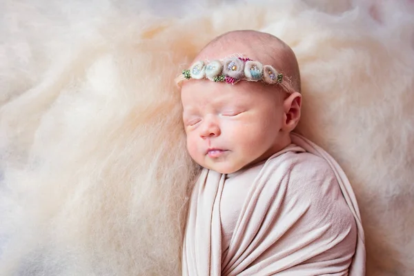 Gyönyörű alvás újszülött lány egy kötést a virágok a fején — Stock Fotó