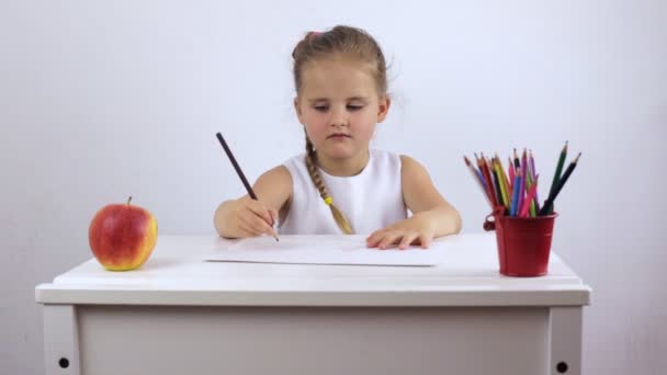 Chica alegre dibuja un cuadro mientras está sentado en la mesa — Vídeos de Stock