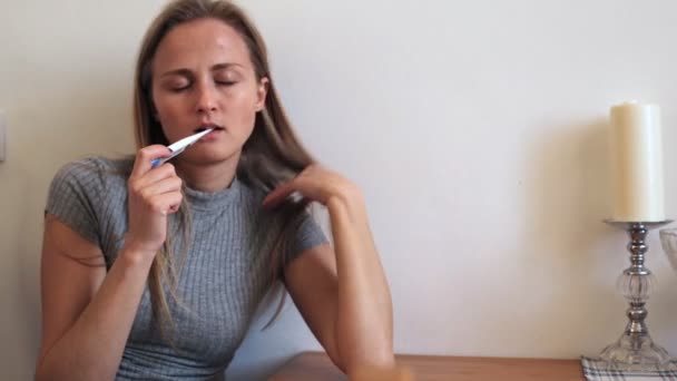 Het meisje meet de lichaamstemperatuur en lijdt aan hitte en migraine — Stockvideo