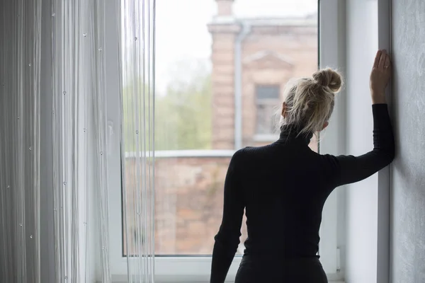 Kadın bekliyor ve pencereden dışarı bakıyor