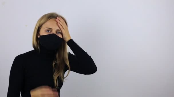 De vrouw heeft ernstige hoofdpijn. Een meisje in een beschermende zwarte masker masseert haar slapen en sluit haar ogen — Stockvideo