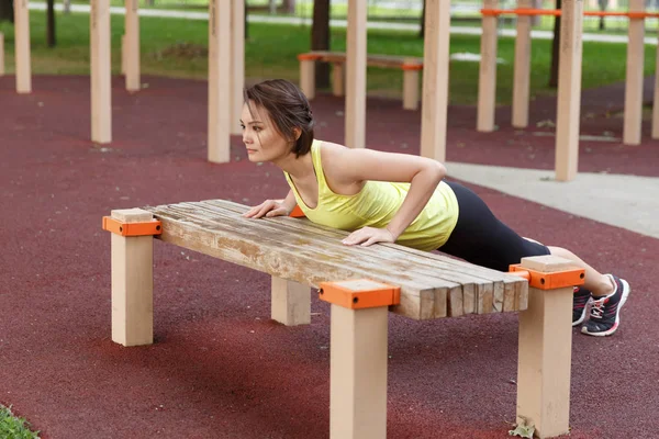 Spor yapan genç bir kadın sokak antrenmanı alanında giyiniyor.