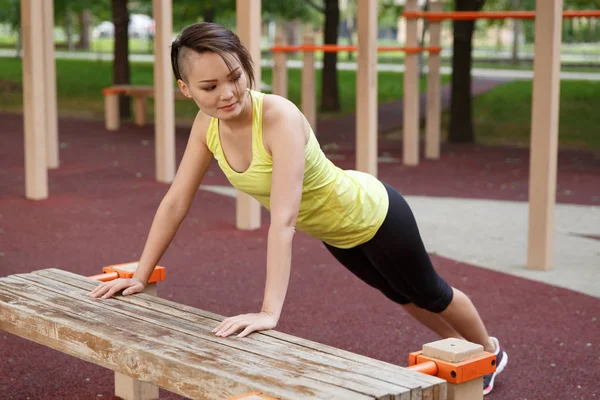 Spor yapan genç bir kadın sokak antrenmanı alanında giyiniyor.