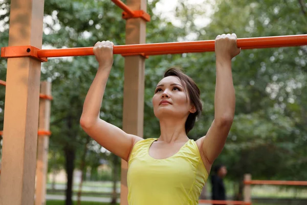 Spor yapan genç bir kadın sokak antrenmanı alanında giyiniyor.