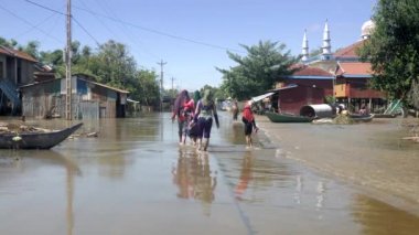 Kampong / Kamboçya / Ağustos 2017: Müslüman kadınlar beyaz camiye yakın sular altında köy yürürken