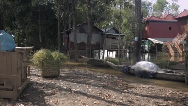 在棚屋下的洪水 院子里有小独木舟 在前景中充满草的竹篮 — 图库视频影像