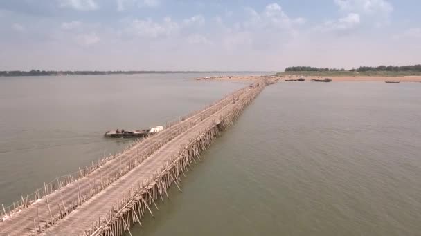 メコン川に架かる竹橋空中の静的なビュー それをくぐる小さな漁船 — ストック動画