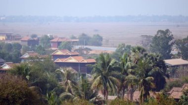 Tropikal bitki örtüsüne ve bir yol üzerinde hareket eden araçlar arasında kırsal kasaba