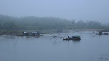 Riverside görünümüne bir balıkçı erken sabah sis Nehri üzerinde Çince balık sudan ağı kaldırma