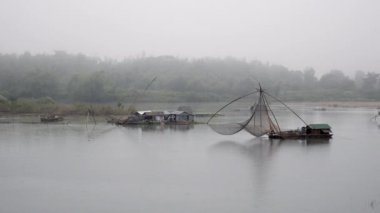 Balık ağı erken sabah sis Nehri üzerinde bir Çin dışında bir el net kullanarak balıklar ele balıkçı görünümüne Riverside yakaladı