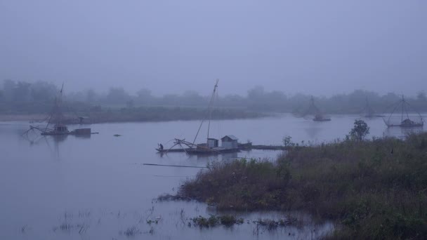 漁師は小型ボートでボートで家から出発します 中国の漁網を背景として早朝の霧の川の上 — ストック動画