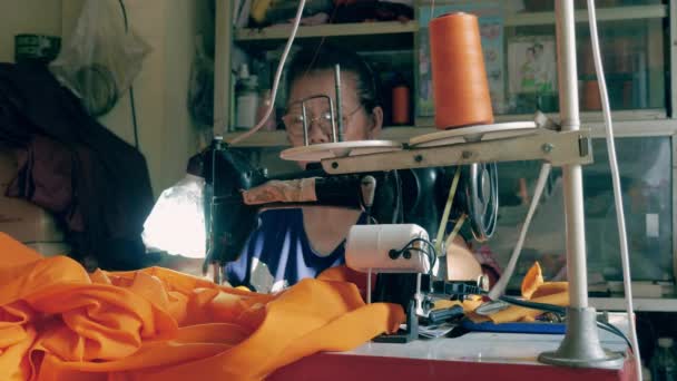 Frau Fertigt Mit Der Nähmaschine Eine Orangefarbene Robe Für Einen — Stockvideo