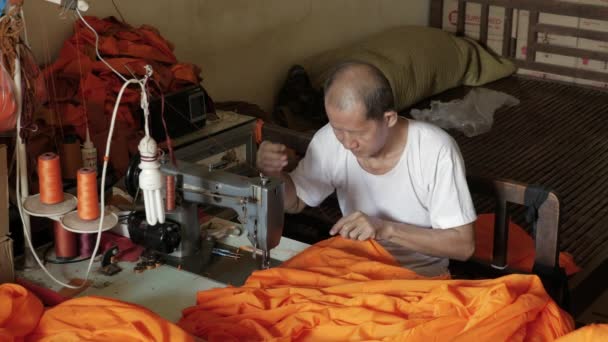 Старик Делает Оранжевую Мантию Монаха Используя Швейную Машинку — стоковое видео
