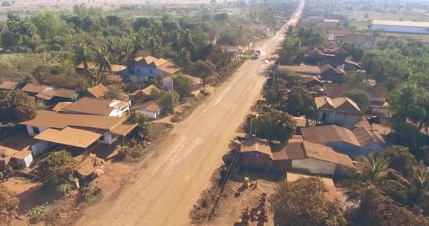 空中无人机射击 在尘土飞扬的道路上飞越经过小村庄的车辆 — 图库视频影像