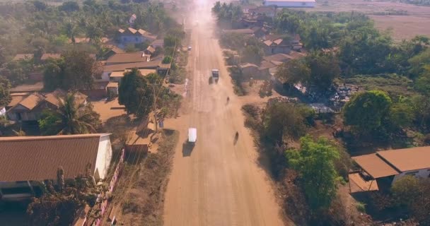 ショット空中ドローン 小さな村を通過してほこりの多い道路で車に戻って飛び  — 無料ストック動画