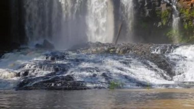 Şelale Close-up dikey olarak büyük kayaların üzerinden güneşli bir günde iner.